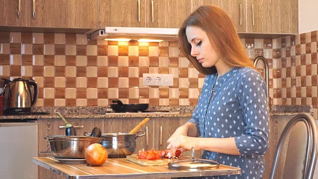 健康饮食生活方式:漂亮女人随便做饭，在厨房切菜。中景，手持，慢镜头60帧/秒。视频素材