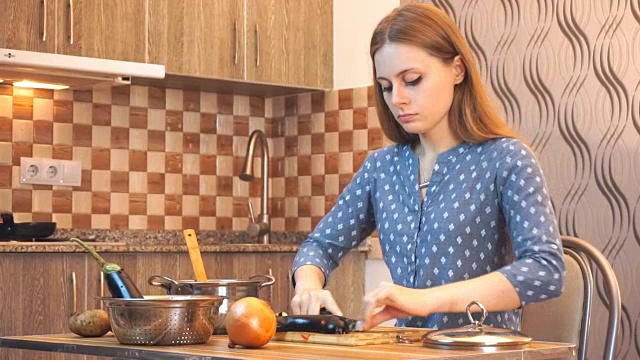 健康饮食生活方式:漂亮女人随便做饭，在厨房切菜。中景镜头,手持。视频素材