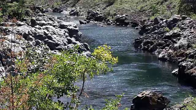 远离镜头的小河流在岩石河岸之间流动视频素材