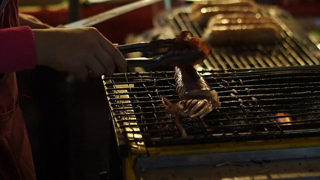 小贩在泰国传统街头食品市场烤鱿鱼视频素材