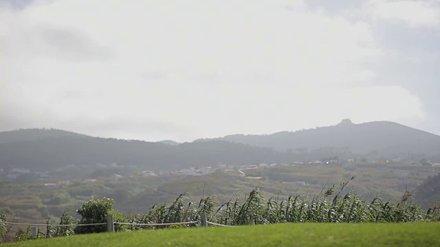 绿色的田野、群山和灰色的夏日天空。多风的天气。葡萄牙卡波达罗卡车站的景观视频素材