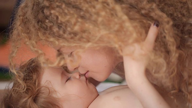 美丽年轻的妈妈温柔地亲吻着熟睡的宝宝，母子俩，孩子们都睡着了视频下载
