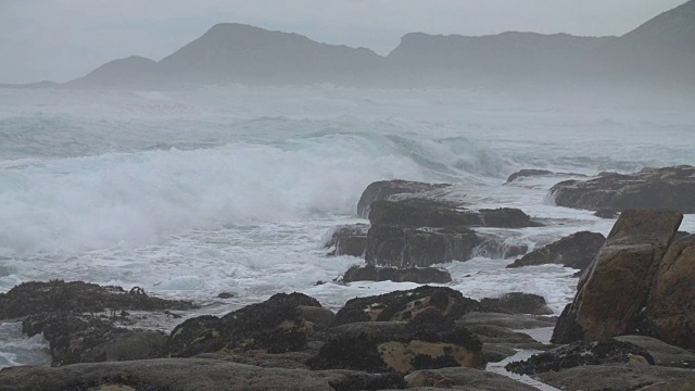 在斯卡伯勒，南非，暴风雨的海浪撞击岩石海滩的慢动作镜头视频素材