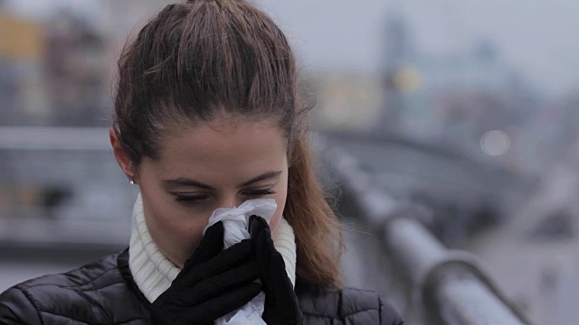 肖像女人打喷嚏和吹鼻子在流感季节城市视频素材