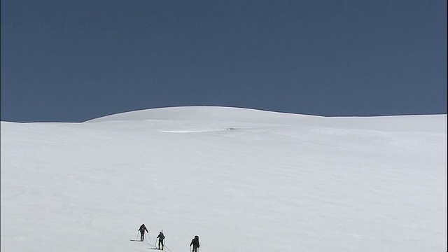 从地平线上缩小到三个登山运动员在白雪覆盖的山脉上行走，加拿大落基山公园，加拿大视频素材