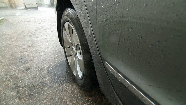 在冰雹中，一个人在下雨的街道上开车视频素材