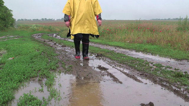 人走在泥泞的道路上，有水坑在雨中视频素材