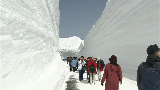 游客们在清理好的道路上陡峭的雪墙之间行走视频素材