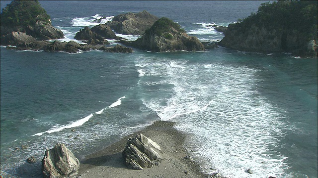 海浪从两边拍打着布满岩石的海滩视频素材