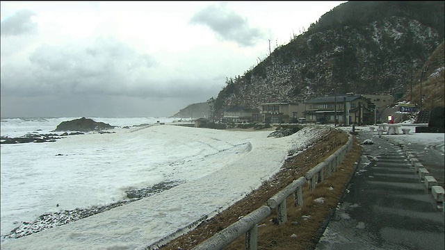 从击碎岩石的海浪中放大，被称为“海浪之花”的泡沫被吹过海滩视频素材