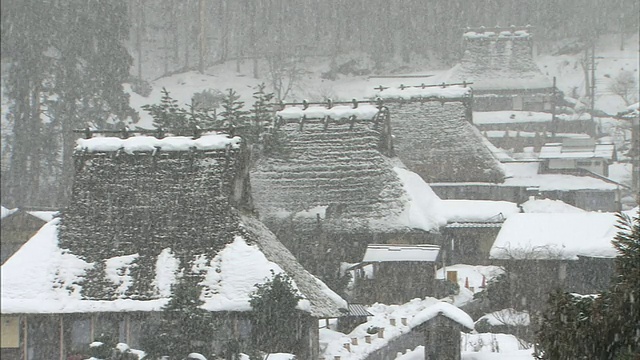 雪落在京都北村一个陡峭的茅草屋顶的村庄。视频素材