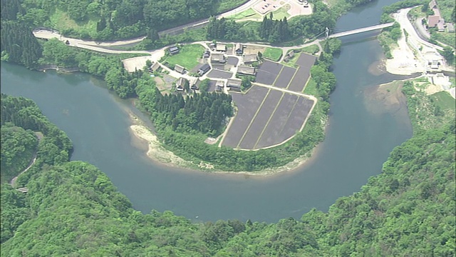 在日本白川古村和戈山古村，陡峭的茅草屋顶俯瞰着稻田。_Aerial拍摄视频素材