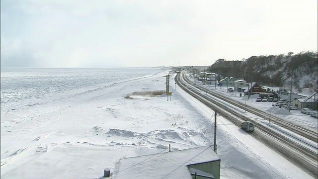 在日本，浮冰侵袭了一条覆盖着积雪的狭窄公路。视频素材