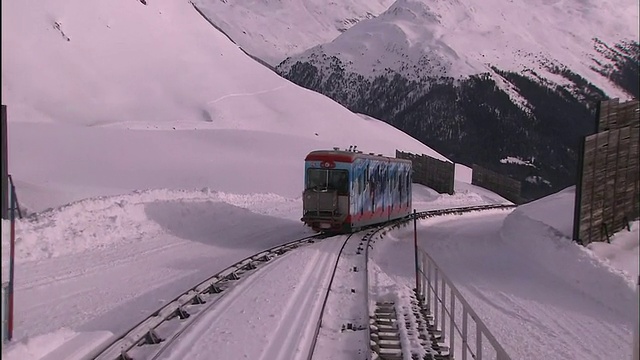 旅客列车在积雪山坡的轨道上行驶。视频素材