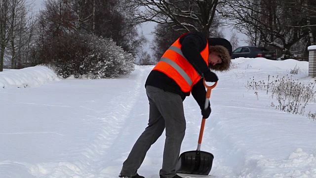 冬天，男人用雪铲在下雪的路上视频素材