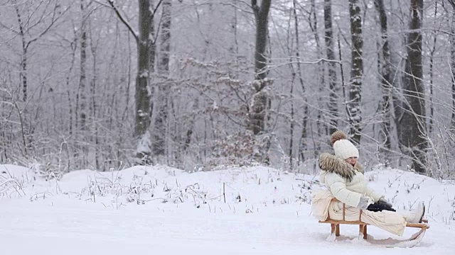 妈妈，宝宝在雪橇上打滚视频素材