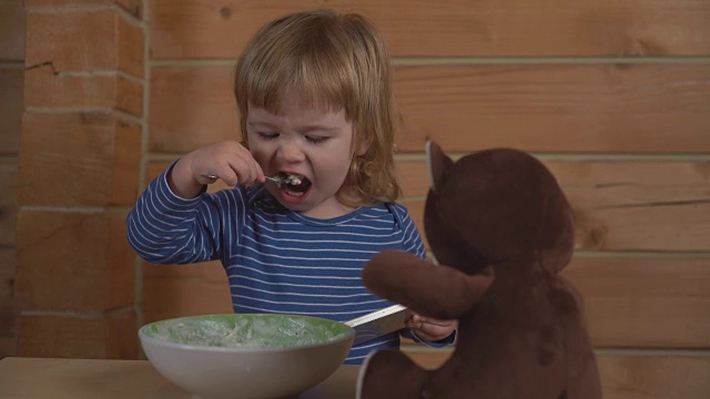 可爱的小婴儿盯着手机，用酸奶油喂小熊吃白软干酪视频素材