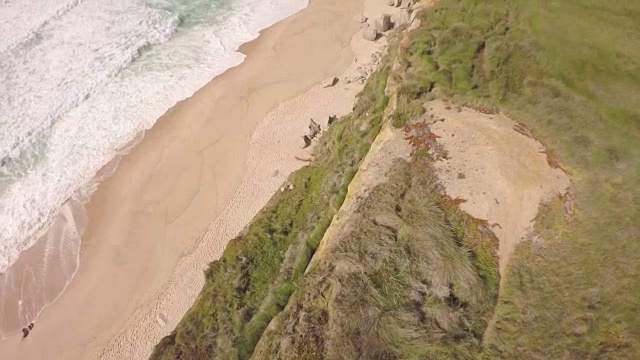 航拍的海边悬崖在普拉亚德圣克鲁斯显示白色的海浪在阳光明媚的一天冲击海滩-托雷斯韦德拉斯，葡萄牙视频下载