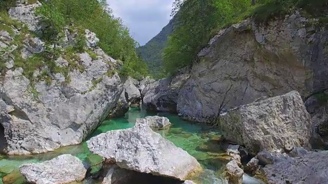 AERIAL:美丽的蓝色山河流经阳光明媚的岩石山谷视频素材