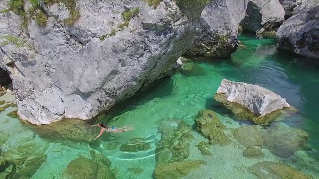 一个女人跳进美丽的山间河流，开始游泳视频素材