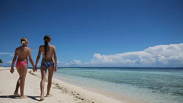 两个女孩在热带海滩上散步视频素材