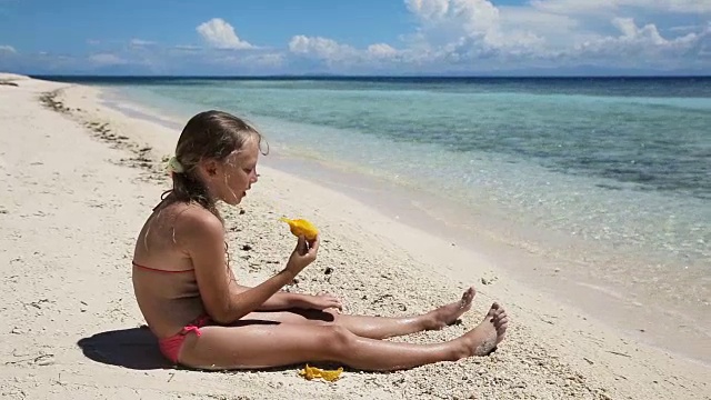 年轻女孩在海滩上吃芒果水果视频素材