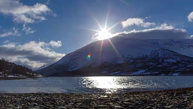 太阳沿着雪山升起，越过多石的海岸视频下载