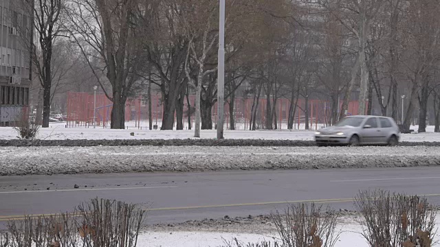 汽车在城市街道上行驶。冬天的时候，雪花飘落。贝尔格莱德城视频素材