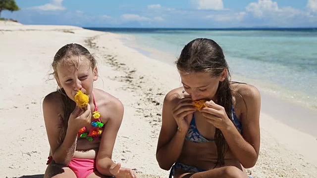 年轻女孩在海滩上吃芒果水果视频素材