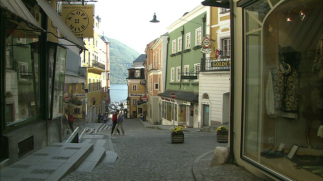 一家人走过特朗西湖(Lake Traunsee)远处的小巷里的商店和老建筑视频素材