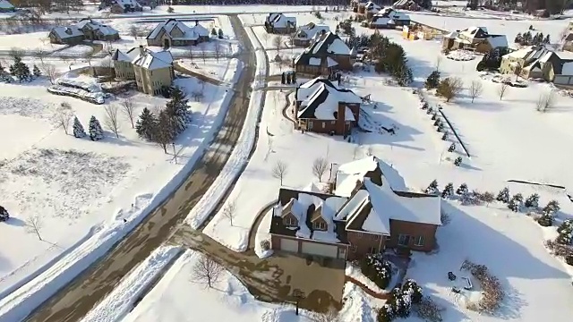 从鸟瞰图看，富裕的郊区住宅被厚厚的冬雪覆盖视频素材