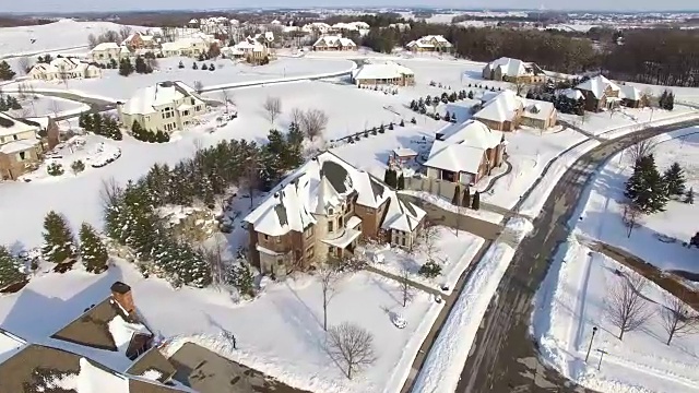 从鸟瞰图看，富裕的郊区住宅被厚厚的冬雪覆盖视频素材