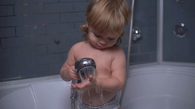 小卷毛男孩在浴室里笑着玩着淋浴视频素材