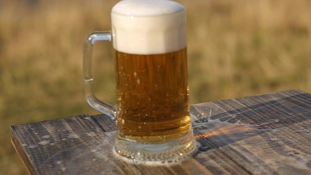 新鲜的啤酒从木桌上的玻璃杯里倒出来视频下载