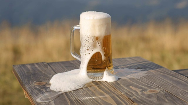 在麦田的背景上，一杯啤酒的泡沫视频素材