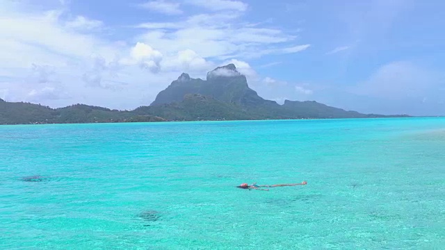 快乐的年轻女子游泳在完美的水晶清澈波拉波拉泻湖在她的暑假视频素材