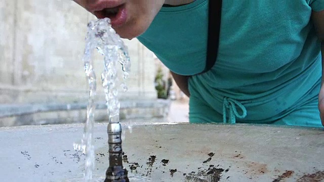 在公共饮水机旁喝着新鲜水的女人:夏天，炎热，温暖视频素材