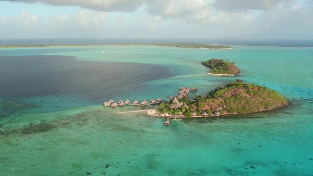 空中飞行:在一个美丽的夏日里，在著名的异国海岛博拉博拉岛(Bora Bora)，在巨大的水晶般清澈的绿松石泻湖中间，飞行在与世隔绝的岛屿度假村和豪华水上别墅视频素材