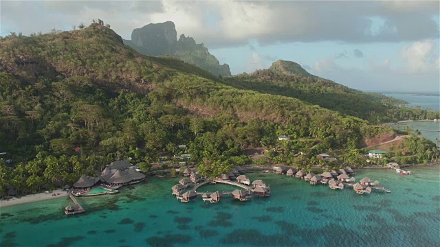 鸟瞰图:在阳光明媚的夏天，在美丽的白色沙滩上，有日光浴躺椅和僻静的海滨平房郁郁葱葱的棕榈树视频素材