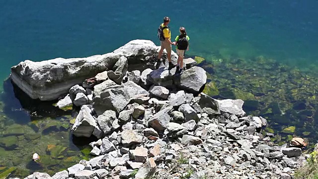 两个背包客走在岩石海岸上视频素材