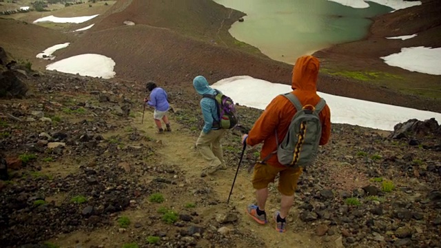 三个徒步旅行者走下一座大山视频素材