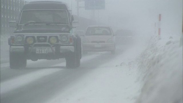 日本，由于暴风雪，汽车在能见度低的道路上行驶视频素材