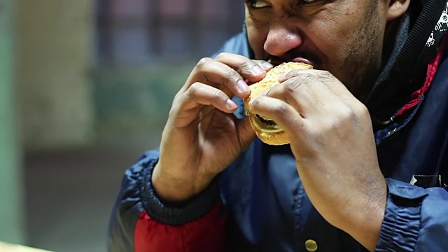 男人在快餐店吃汉堡，不健康的饮食很危险视频素材