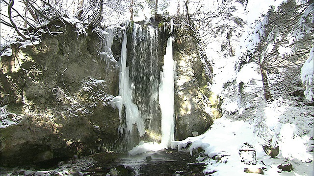 在白雪覆盖的景观中，水流从Fudo瀑布流出。视频素材