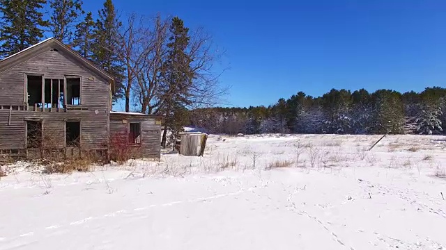 风景优美的废弃的房子与白雪覆盖的树林和田野视频素材