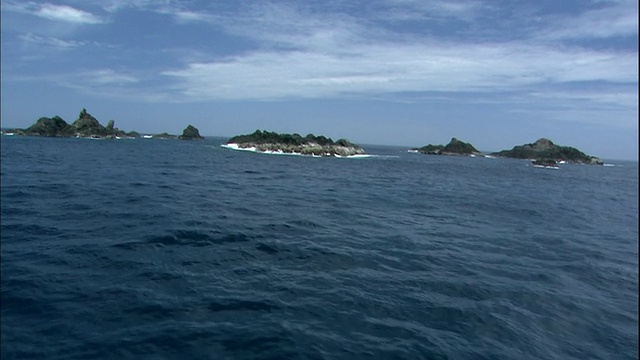 巨大的白浪拍打在小笠原群岛海岸周围的岩石上。视频素材