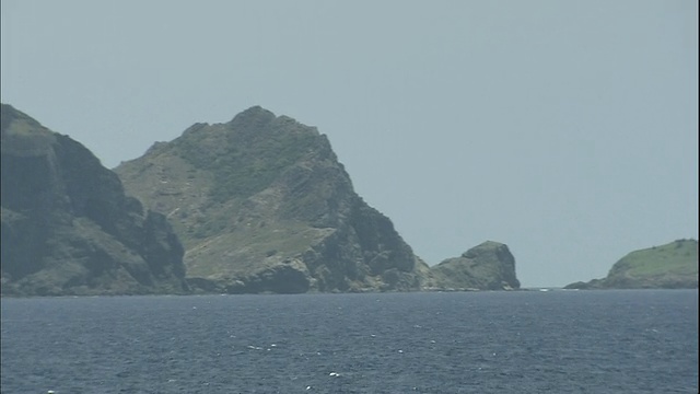 雾蒙蒙的天空勾勒出太平洋上的日本知岛(Chichi-Jima Islands)。视频素材