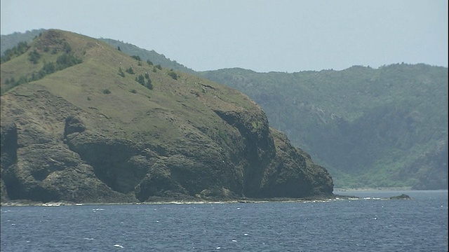 阴霾的天空勾勒出太平洋上日本小笠原群岛沿海山脉的轮廓。视频素材