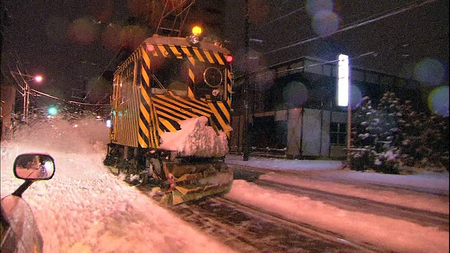 日本札幌，一辆除雪车在清扫有轨电车线上的积雪，雪花从车上飞落下来。视频素材