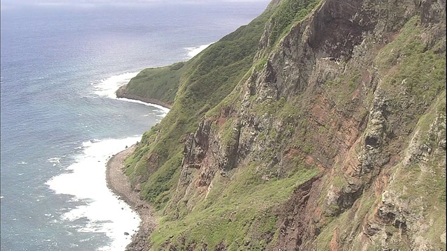 白色的海浪包围着太平洋上的北硫黄岛的陡峭悬崖。视频素材